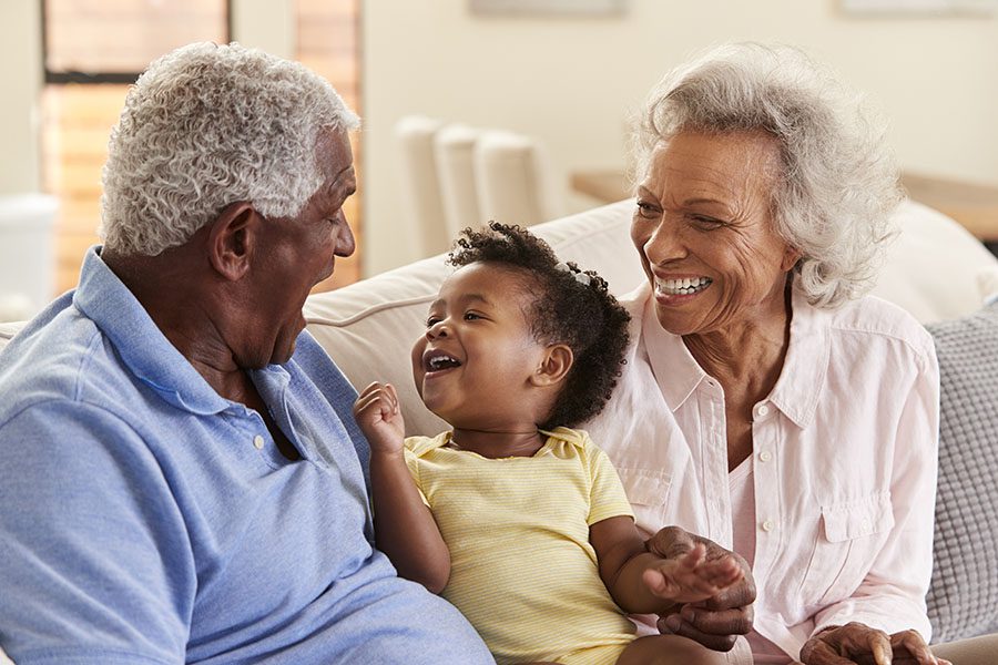 Health Insurance - Happy Grandparents Sitting on the Sofa Playing with Their Grandaughter