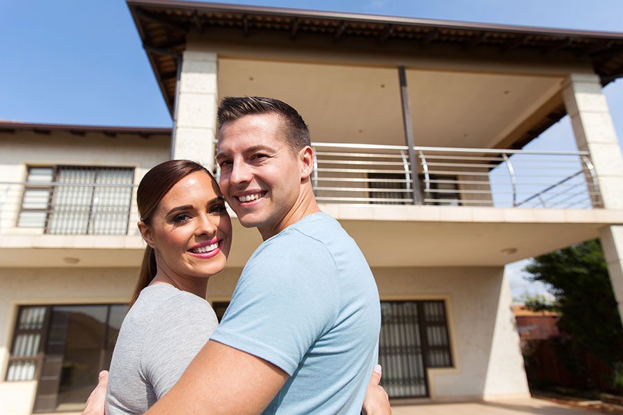 Personal Insurance - View of Happy Young Couple Standing in Front of Their New Home