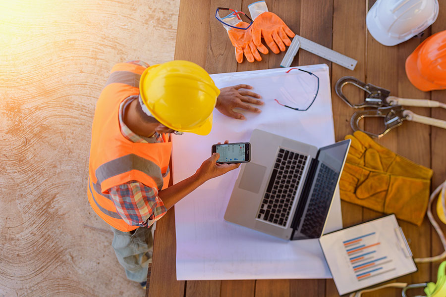 Specialized Business Insurance - View of a Contractor Using a Phone and Looking at Building Plans